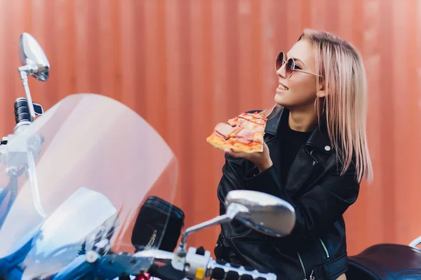 Chica comiendo una deliciosa pizza mientras está sentado en una motocicleta . —  Fotos de Stock