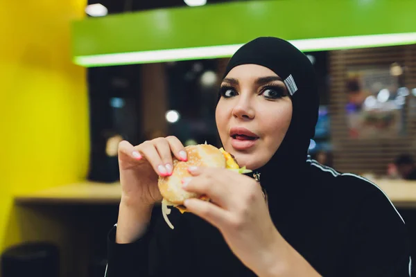 Arabské dívky v fast food restaurace jíst burger. — Stock fotografie