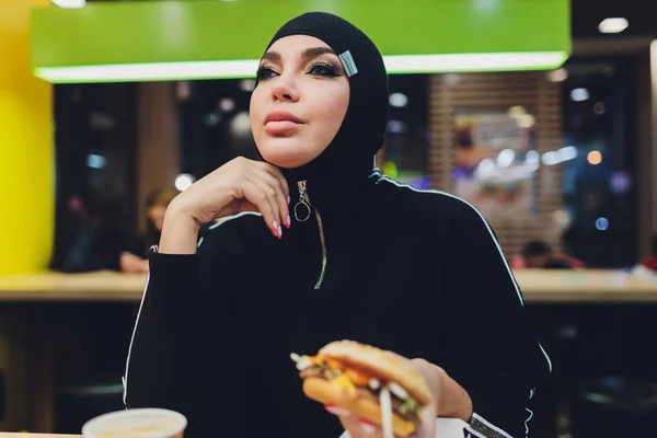 Chicas árabes en restaurante de comida rápida comiendo hamburguesa . — Foto de Stock