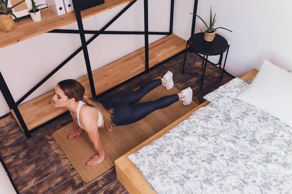 Attrayant fitness femme faire des exercices d'étirement à la maison, dans le cadre d'un mode de vie sain sans aller à la salle de gym . — Photo