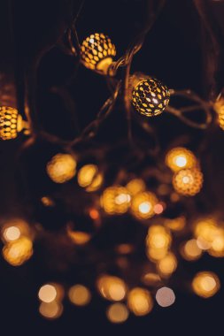 Koyu sarı arka planda bulanık Noel ışıkları. Çözülmüş Noel çelengi, kopyalanmış boşluk.