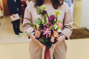 Olağandışı bir gelinin elinde turuncu ve beyaz çiçekli şık buket düğün.