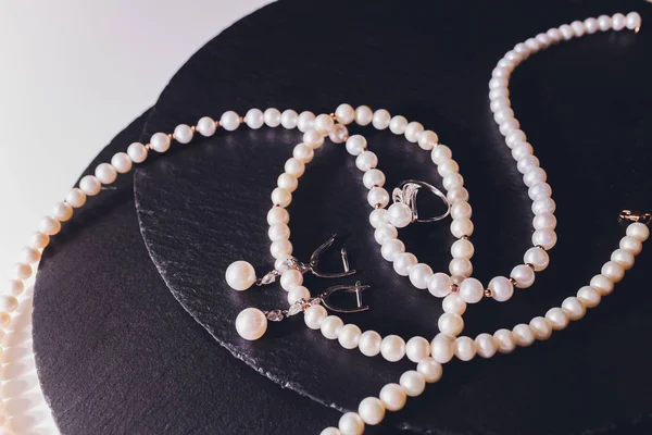 White pearl necklace on a black silk close up. — Stock Photo, Image