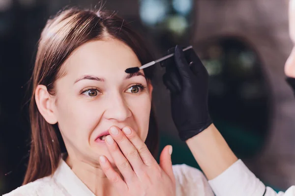 Esteticista-artista de maquillaje aplica henna pintura en previamente arrancado, diseño, cejas recortadas en un salón de belleza en la corrección de la sesión. Cuidado profesional de la cara. —  Fotos de Stock