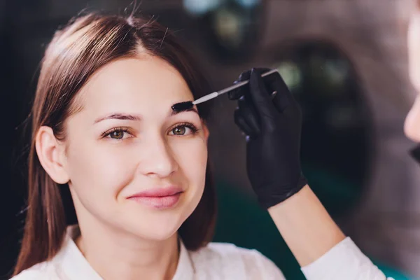 Vacker-makeup artist tillämpa måla henna på tidigare plockade, design, trimmade ögonbryn i en skönhetssalong i sessionen korrigering. Professionell ansiktsvård. — Stockfoto