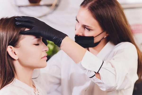 Esteticista-artista de maquillaje aplica henna pintura en previamente arrancado, diseño, cejas recortadas en un salón de belleza en la corrección de la sesión. Cuidado profesional de la cara. —  Fotos de Stock