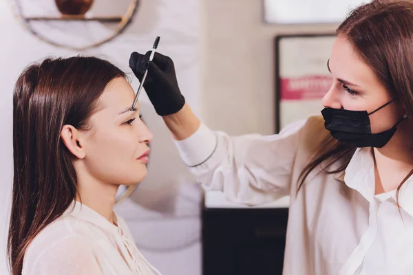 Vacker-makeup artist tillämpa måla henna på tidigare plockade, design, trimmade ögonbryn i en skönhetssalong i sessionen korrigering. Professionell ansiktsvård. — Stockfoto