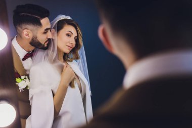 Güzel yeni evliler aynanın karşısında ışıklarla oturuyorlar ve aynada yansıtılıyorlar. Stüdyoda şık bir düğün..