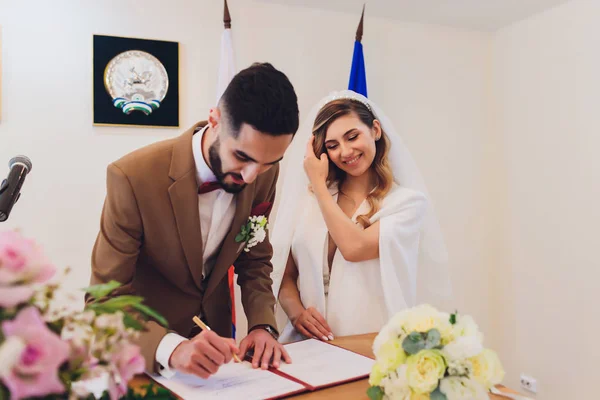 Newlyweds append signatures in a registry office during wedding registration. — Stock Photo, Image