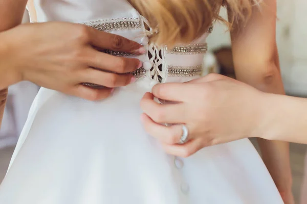 Bruid haar witte trouwjurk te zetten. Bruiloft feest concept. Prachtige kanten trouwjurk van de bruid met open rug. — Stockfoto