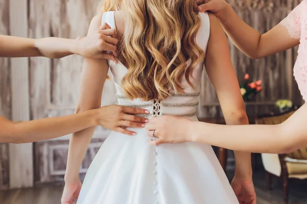 Bruid haar witte trouwjurk te zetten. Bruiloft feest concept. Prachtige kanten trouwjurk van de bruid met open rug. — Stockfoto