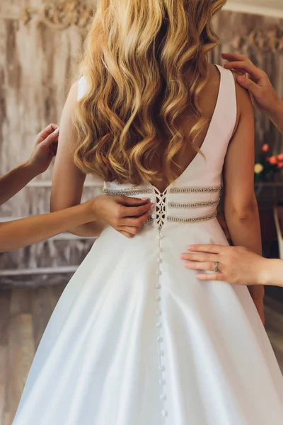 花嫁は彼女の白いウェディング ドレスに置きます。結婚式のお祝いのコンセプト。オープン バックと花嫁の美しいウェディング ドレス. — ストック写真