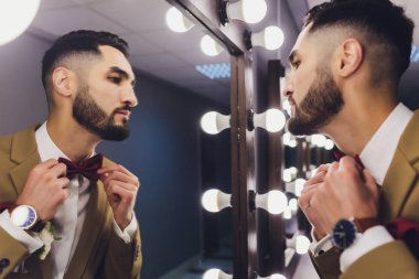 Yakışıklı güçlü şık sakallı damat ayna yakınında poz.