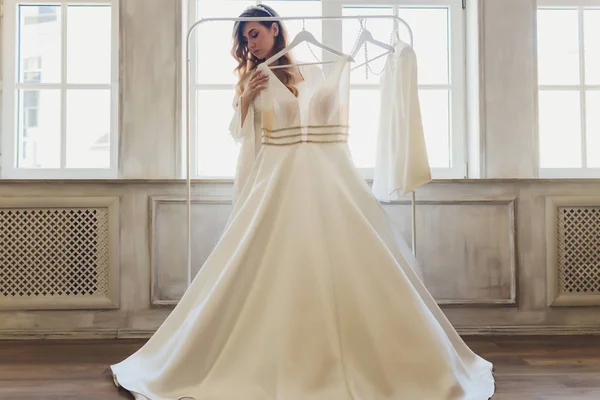 Молодая милая брюнетка невеста смотрит на свое свадебное платье . — стоковое фото