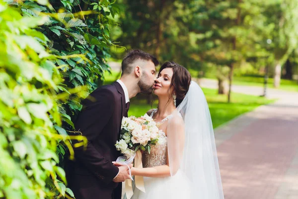 Šťastný ženich a nevěsta v parku na jejich svatební den. — Stock fotografie