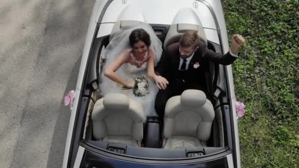 Щаслива наречена цілує нареченого, молода весільна пара керує кабріолетним ретро-автомобілем з повітряними кульками на заміській дорозі на медовий місяць після церемонії. Шлях. Найкращий день і шлюб. Просто одружився . — стокове відео