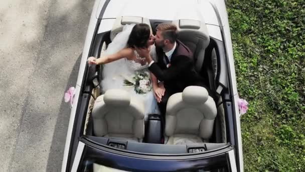 Noiva feliz beijo noivo, casal recém-casado está dirigindo um carro retro conversível com balões em uma estrada rural para a lua de mel após a cerimônia. Muito bem. O melhor dia e casamento. Casado. . — Vídeo de Stock