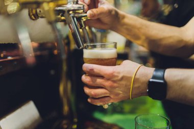 Barmen fıçıdan bardağa bira doldurur..