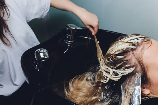 Close-up van Kapper handen haren van mooie jonge vrouw scheiden met aluminiumfolie voordat veranderen de kleur van het haar. — Stockfoto