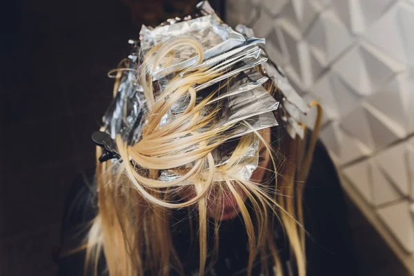 Closeup των χεριών κομμωτήριο που χωρίζει τα σκέλη των μαλλιών του όμορφη νεαρή γυναίκα με φύλλο αλουμινίου πριν αλλάξετε το χρώμα των μαλλιών. — Φωτογραφία Αρχείου