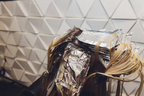 Nahaufnahme von Friseurhänden, die Haarsträhnen einer schönen jungen Frau mit Alufolie trennen, bevor sie die Haarfarbe ändern. — Stockfoto