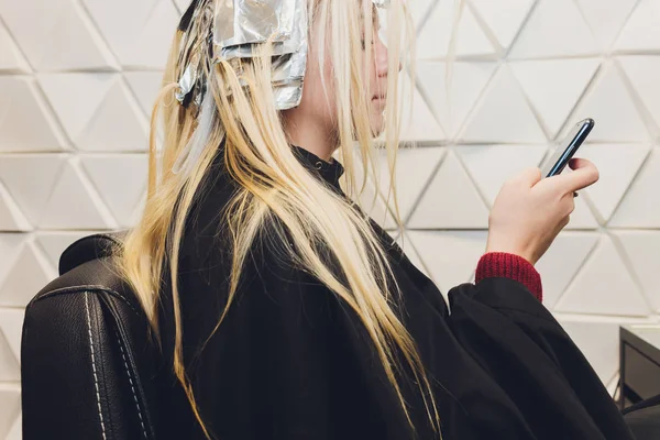 Close-up van Kapper handen haren van mooie jonge vrouw scheiden met aluminiumfolie voordat veranderen de kleur van het haar. — Stockfoto