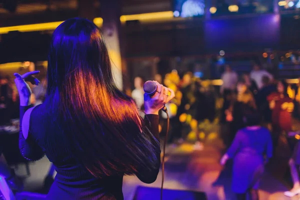 Piękny śpiew dziewczyny. Piękna blask moda kobieta z mikrofonem na migające tło bokeh w nocy. Glamour Model piosenkarka. Piosenki karaoke. Karaoke party. — Zdjęcie stockowe