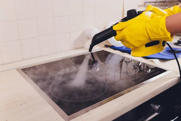 Cleaning kitchen hob with a steam cleaner. — Stock Photo, Image