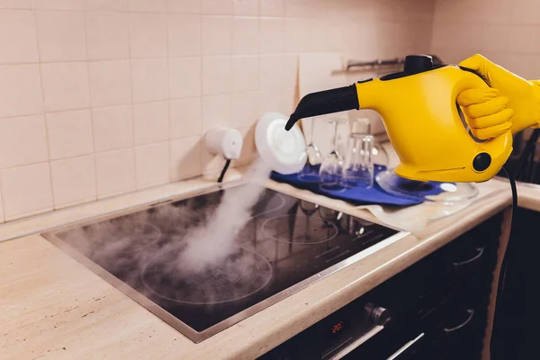 Nettoyage de la plaque de cuisson avec un nettoyeur à vapeur . — Photo