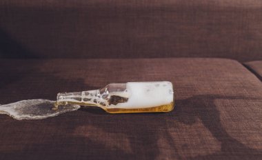 Ailede alkolizm var. Bira şişesi ve kanepeye dökülmüş bira..