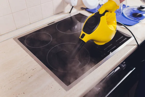 Limpeza de placa de cozinha com um aspirador de vapor . — Fotografia de Stock