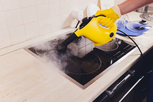 Nettoyage de la plaque de cuisson avec un nettoyeur à vapeur . — Photo