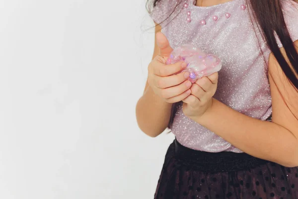 Ung flicka som leker med slem. Isolerad på vit bakgrund. — Stockfoto