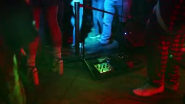 Genç hippi kadın bacakları ve kırmızı gitarın neon ışıklarıyla yakın plan fotoğrafı. Rock müzisyeni elektro gitar çalıyor..