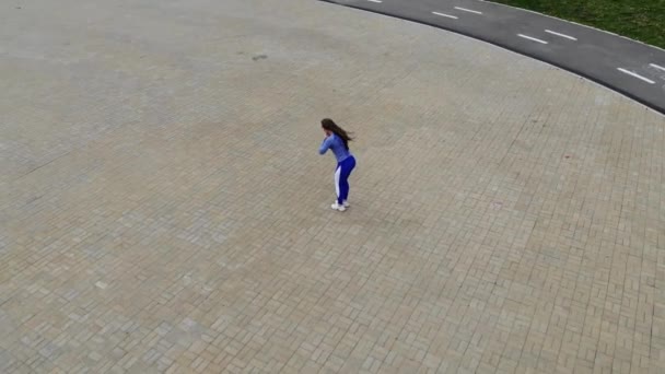 Draufsicht auf die Rückseite einer jungen attraktiven, athletischen Frau, die an einem sonnigen Sommertag morgens auf dem Asphalt der Stadt läuft und trainiert. Läuferinnen trainieren im Freien. — Stockvideo