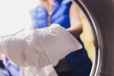 Çamaşırları kuru temizlemecideki çamaşır makinesine yüklemek için eller havaya..