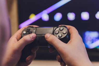 Playing games concept. Part body man with joystick play game on console. Male hands holding grey pad.