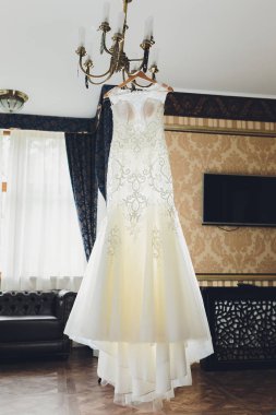 Bej renkli gelinlik peg avize üzerinde asılı.