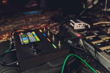 Electric guitar and guitar audio processing effects on a studio floor. Electric guitar and stomp box type effectors and cables on studio floor. Intentionally shot with low key tone.