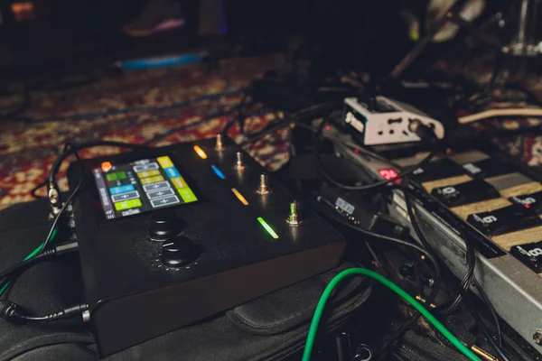 Electric guitar and guitar audio processing effects on a studio floor. Electric guitar and stomp box type effectors and cables on studio floor. Intentionally shot with low key tone. — Stok fotoğraf