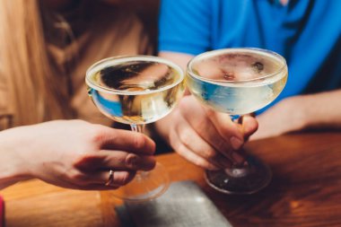 Bokeh arkaplanının önünde kadeh tokuşturup şampanya içen bir grup insanı yakından çek. Yaşlı insanların elleri.