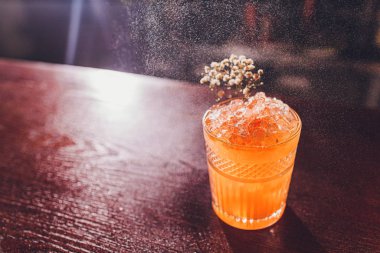 Bulanık arka planda Bar sayacı üzerinde cam lezzetli şeffaf kırmızı kokteyl püskürtme profesyonel erkek barmen.