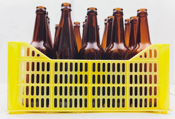Пиловий вінтажний жовтий пивний ящик з порожніми пляшками коричневого пива на білому тлі . — стокове фото