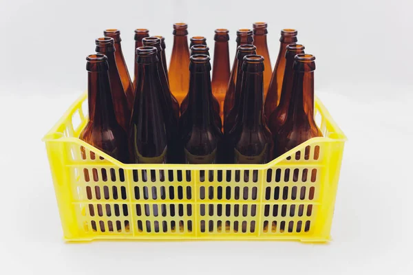 Caja de cerveza amarilla vintage polvorienta con botellas de cerveza marrón vacías sobre fondo blanco . —  Fotos de Stock