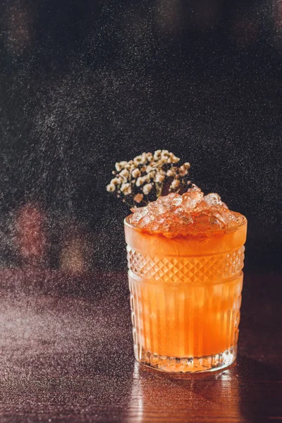 Professionele mannelijke barman spuiten op de heerlijke transparante rode cocktail in het glas op de bar teller in de wazige achtergrond. — Stockfoto