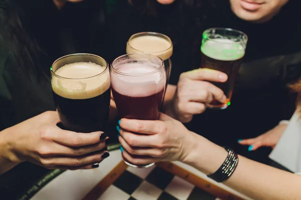 Hände halten Biergläser in der Kneipe, eine Gruppe von Freunden genießt die Bierzeit in der Stadt, aus nächster Nähe auf den Gläsern. — Stockfoto