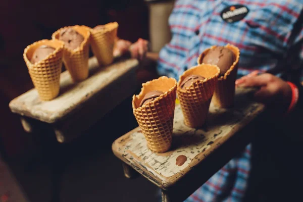 Вафлі з шоколадною начинкою на дерев'яному підносі. Вафельні роги з сиром посипані шоколадом . — стокове фото