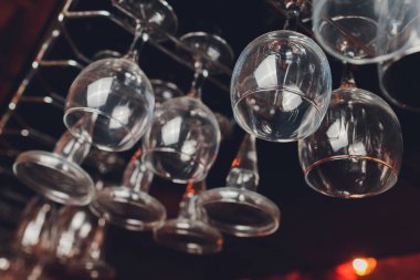 Closeup çok baş aşağı boş şeffaf şeffaf kristal ters şarap bardakları kahverengi ahşap raf, raf, vitrin, paslanmaz çelik korkuluk barda düz sıralar asılı, dolap.