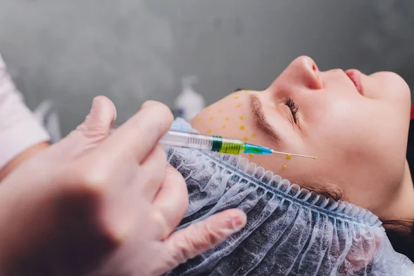 De arts cosmetoloog maakt de biorepil gezichtsinjecties procedure voor aanscherping en gladstrijken rimpels op de gezichtshuid van een mooie. — Stockfoto