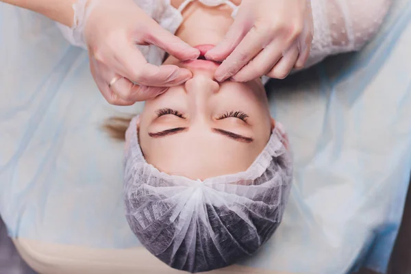 Kosmetolog vyrábí bukové masáže pacientů na obličejové svaly. — Stock fotografie